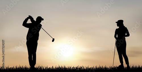 Couple of golfers at sunset. A man and a woman play golf at sunset. Two people are playing golf