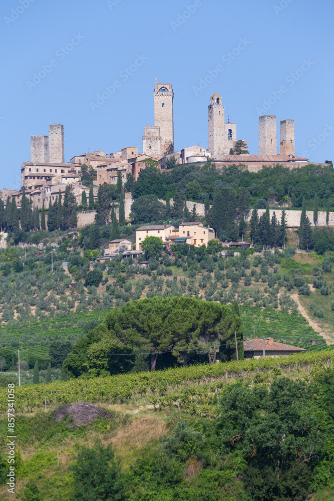 San Gimignano village, Italy: green countryside, blue sky, hill panorama with town and towers San Gimignano village, Italy: green countryside, blue sky, hill panorama with town and towers