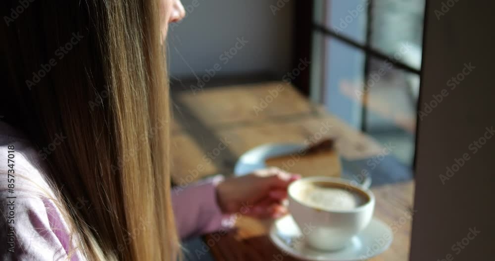 Woman takes small sip of delicious coffee sitting near cafe window in sunny morning closeup. Female enjoys decaffeinated beverage in city vintage coffeeshop Woman takes small sip of delicious coffee sitting near cafe window in sunny morning closeup. Female enjoys decaffeinated beverage in city vintage coffeeshop