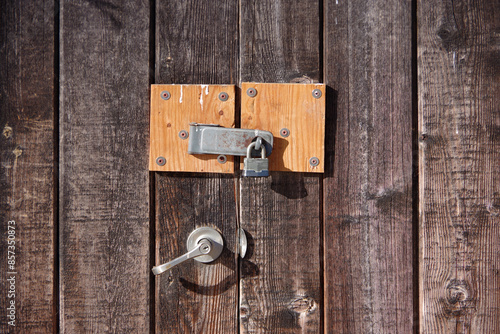 Padlock and latch on a wooden building entrance gate