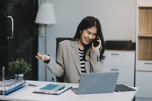 Elegant millennial Asian businesswoman using her smartphone at her desk. text, chat, message, sms, mobile application, online shopping.