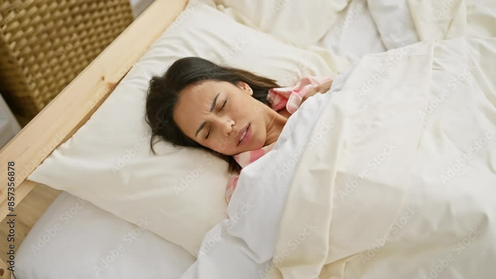 A serene woman comfortably sleeping in a bright bedroom with white linens and a wooden bedframe. A serene woman comfortably sleeping in a bright bedroom with white linens and a wooden bedframe.