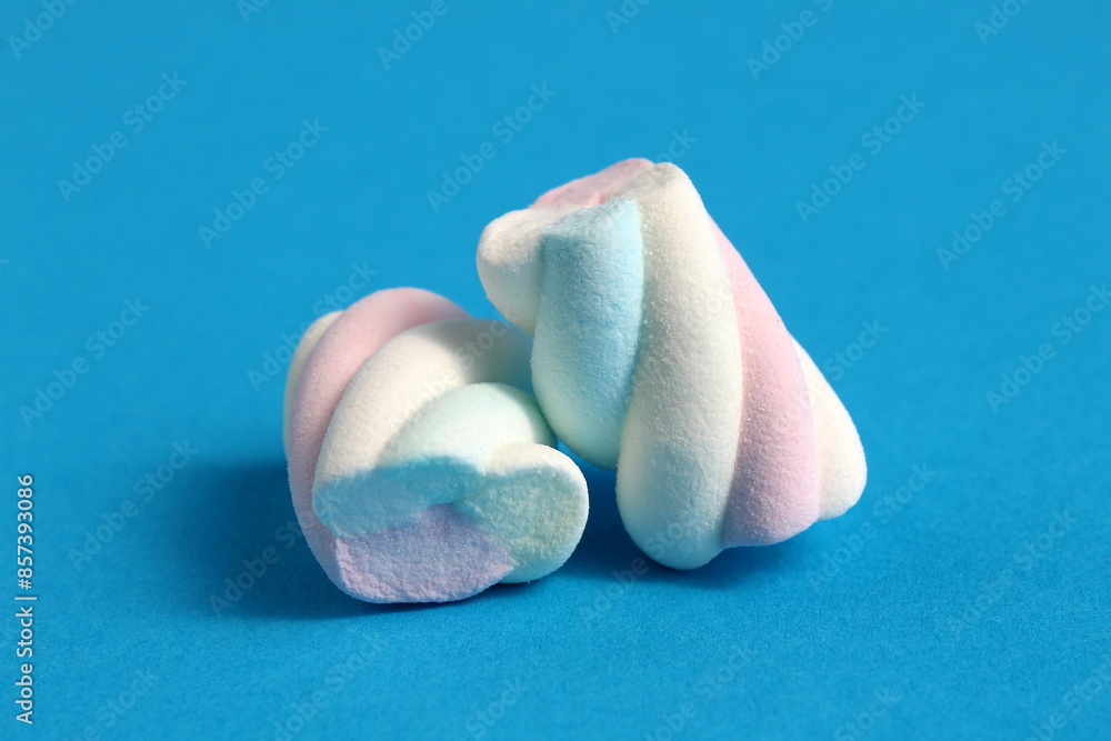 Two marshmallows lie on a blue background. Two marshmallows lie on a blue background.