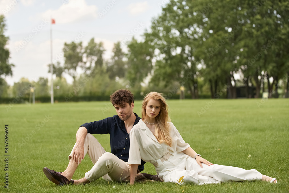 A stylish young couple in elegant attire, relaxing together on the lush green grass of a park. A stylish young couple in elegant attire, relaxing together on the lush green grass of a park.
