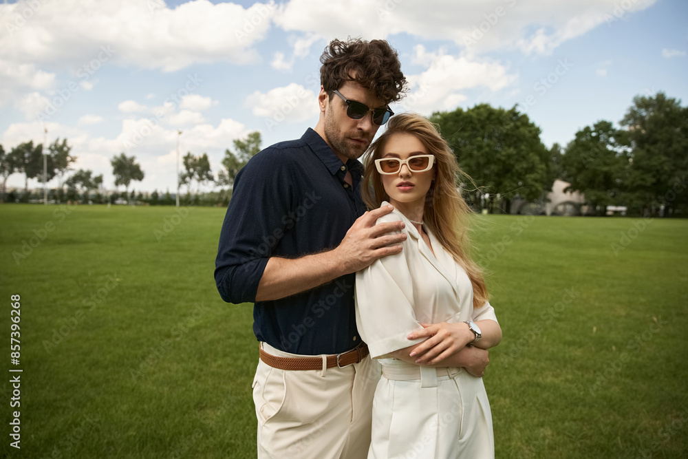 A man and woman, elegantly dressed, stand together in a lush green field, embodying a life of luxury and sophistication. A man and woman, elegantly dressed, stand together in a lush green field, embodying a life of luxury and sophistication.