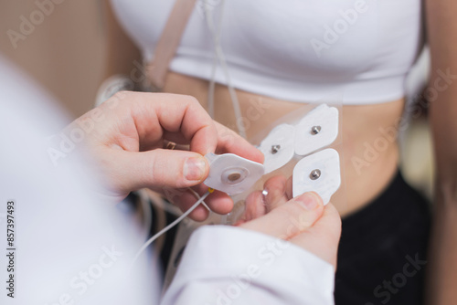 Photos Medical worker placing electrodes on a patient's chest for a cardiology examination