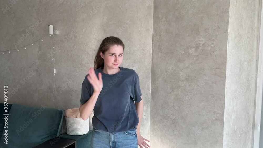 Young woman energetically dances in a modern minimalist living room, expressing joy and carefree movement against a neutral wall background Young woman energetically dances in a modern minimalist living room, expressing joy and carefree movement against a neutral wall background