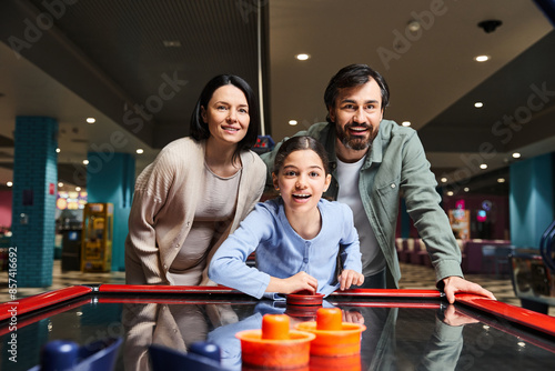 Принти на полотні A happy family competes in a game of air hockey at an arcade, laughing and enjoying a fun weekend together