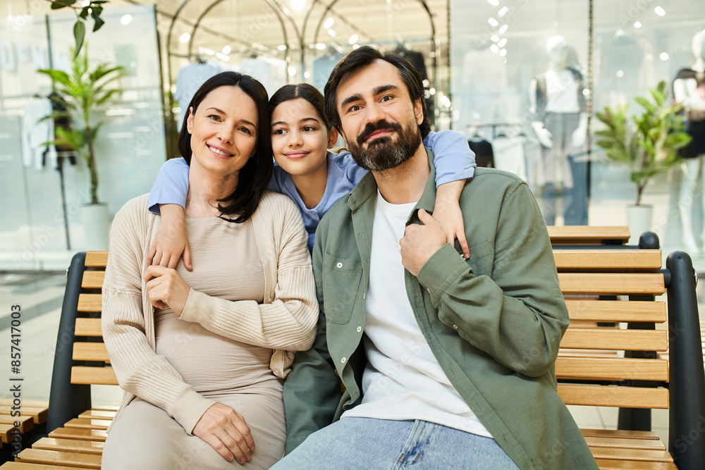 Fototapeta premium A joyful family relaxes on a bench in a busy shopping mall, enjoying a bonding moment together amid the hustle and bustle.
