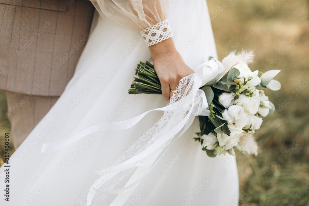 Close-up wedding couple bride and groom walk hand in hand through a pine forest, sunlight filtering through the trees, high lighting their joyful expressions.