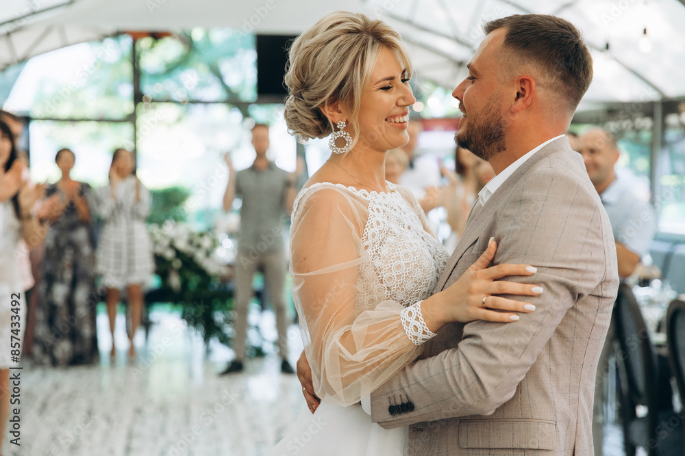 Bride and groom dancing the first wedding dance against the background of guests in an evening restaurant Bride and groom dancing the first wedding dance against the background of guests in an evening restaurant