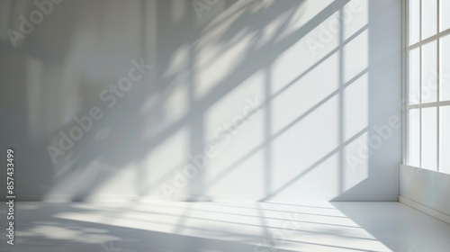 A bright, white room with a large window casting stripes of light onto the white wall and floor.