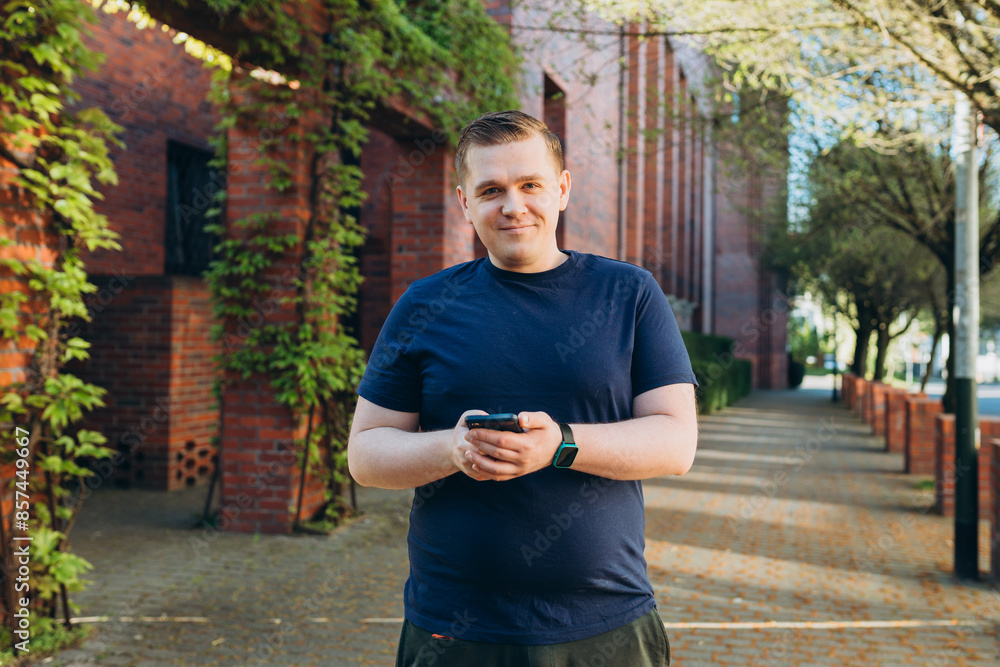Young 30s man smiling confident using smartphone at street. Communication and gadgets, connection concept. Man holding on cell smartphone while relaxing outdoors, Urban lifestyle banner