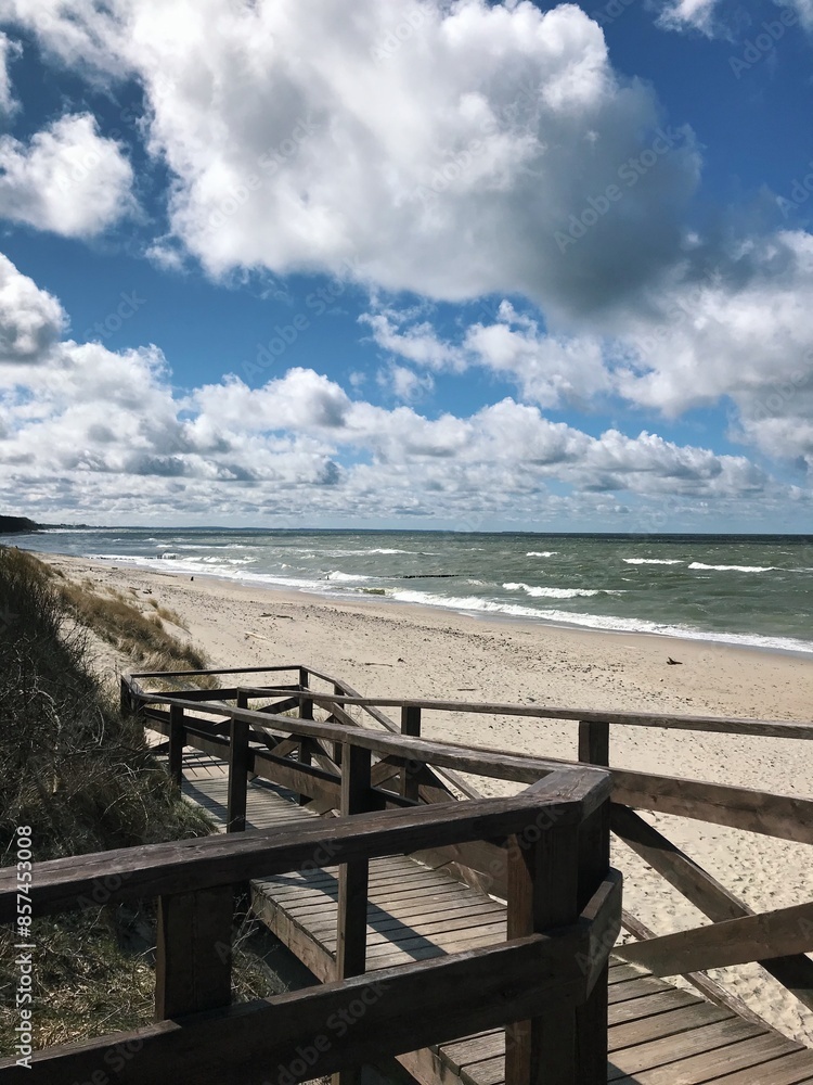 wooden stairs going down to the beach, sandy beach and white clouds wooden stairs going down to the beach, sandy beach and white clouds