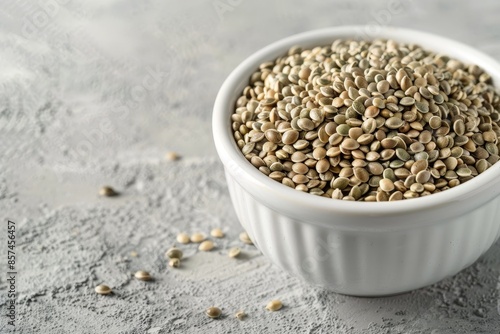 Whole dried hemp seeds in a white bowl on a light gray table Hemp seeds for cooking