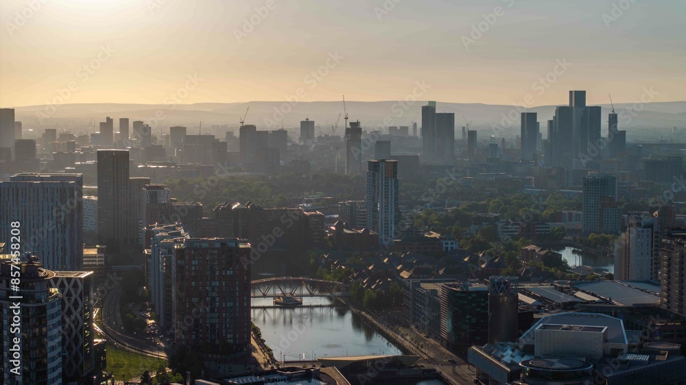 Fototapeta premium A tranquil sunrise view over Manchester's skyline with glimpses of Deansgate and Salford Quays in the warm morning light