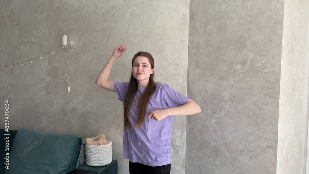 Young woman showcasing fluid and dynamic expressive dance moves in a minimalist living room with modern decor and natural lighting Young woman showcasing fluid and dynamic expressive dance moves in a minimalist living room with modern decor and natural lighting