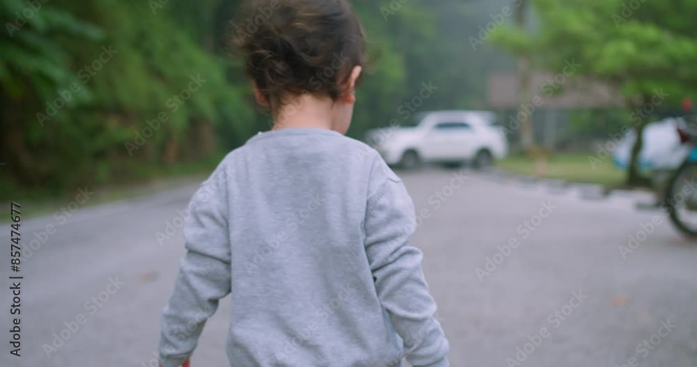 A young child in casual clothing walking on a road in a nature park, surrounded by greenery in Background on a Misty Day A young child in casual clothing walking on a road in a nature park, surrounded by greenery in Background on a Misty Day