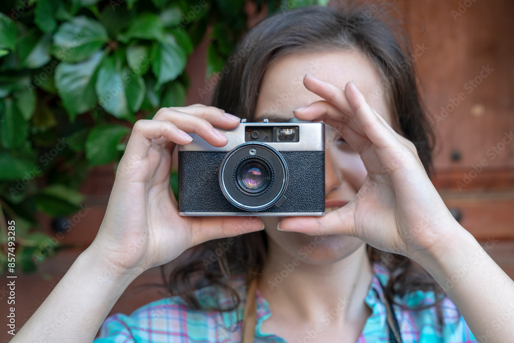 A woman holds an old camera and looks through the viewfinder A woman holds an old camera and looks through the viewfinder