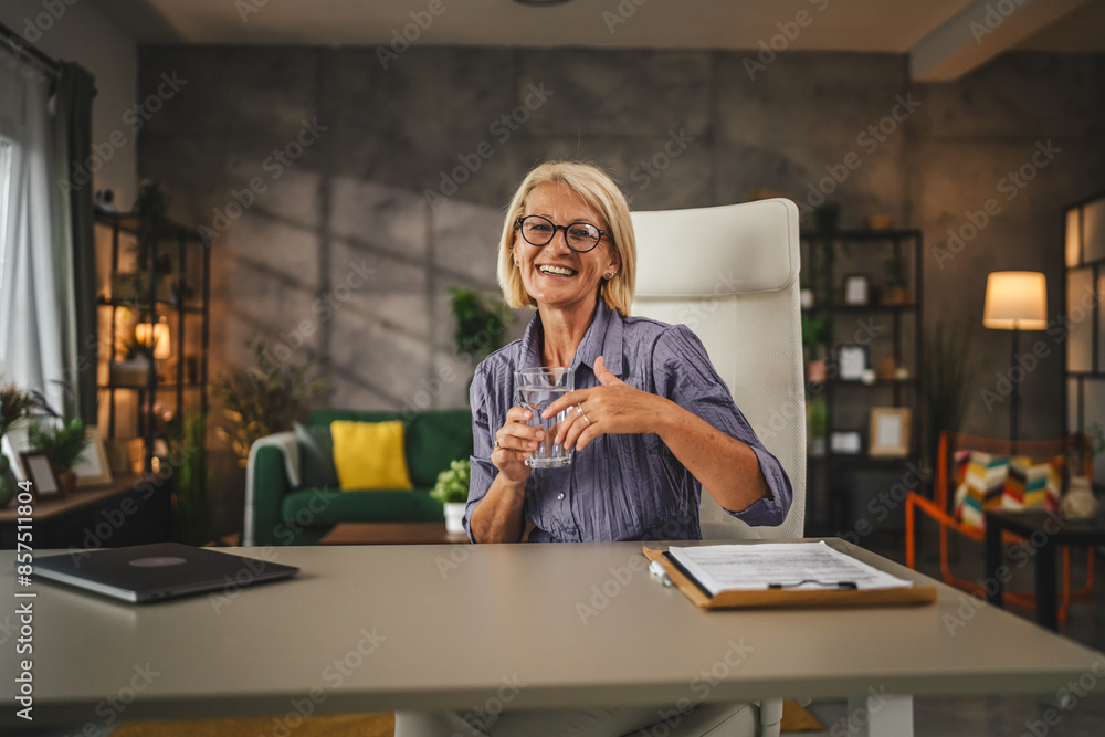 Portrait of mature woman sit, smile and hold glass of water at home Portrait of mature woman sit, smile and hold glass of water at home