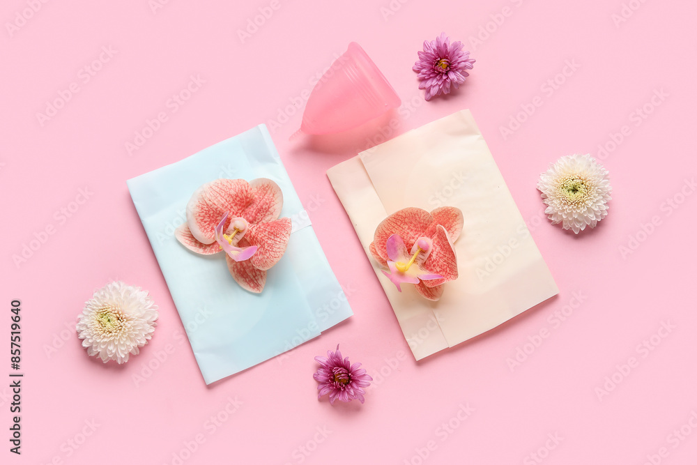 Menstrual cup with pads and flowers on pink background Menstrual cup with pads and flowers on pink background