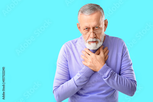 Ill old man with sore throat on blue background © Pixel-Shot