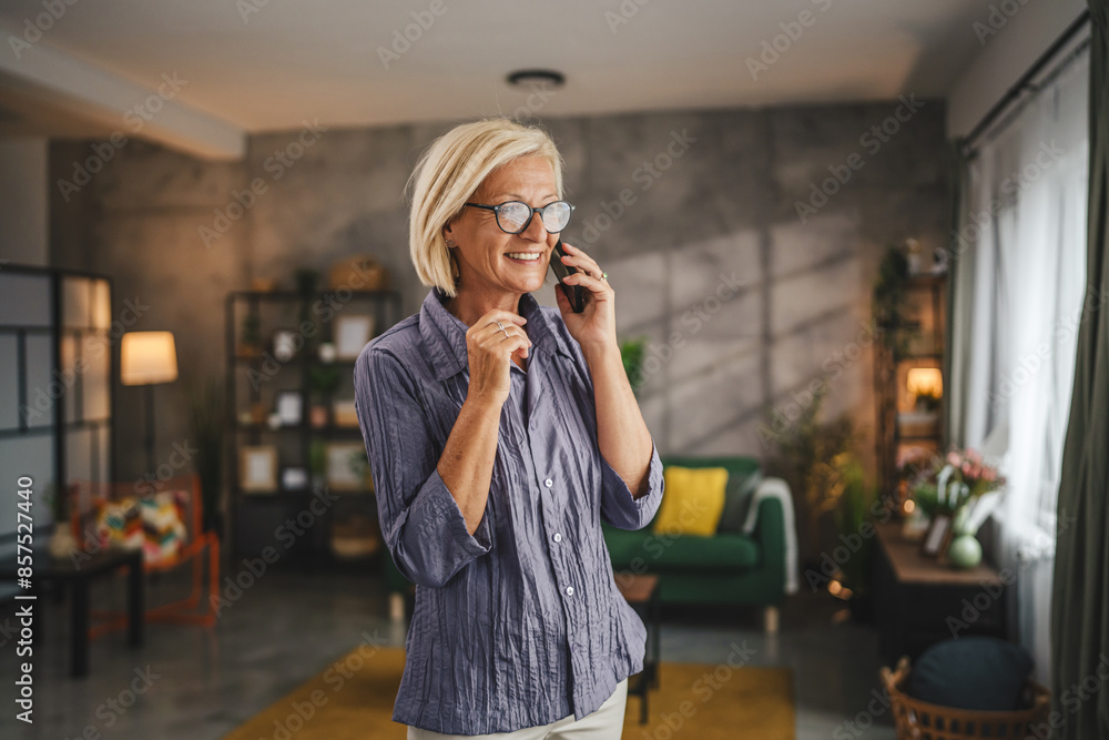 Fototapeta premium One mature blonde woman stand at home use mobile phone talk