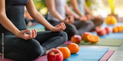 Fototapeta Naklejka Na Ścianę i Meble -  A group of people practicing meditation while sitting on yoga mats in a tranquil studio setting, surrounded by various fruits like apples and oranges to promote wellness.