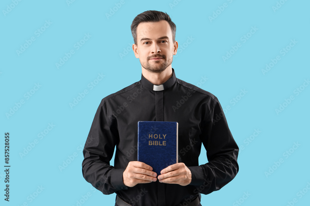 Portrait of male priest with holy Bible on blue background Portrait of male priest with holy Bible on blue background