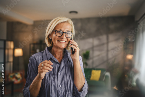 One mature blonde woman stand at home use mobile phone talk