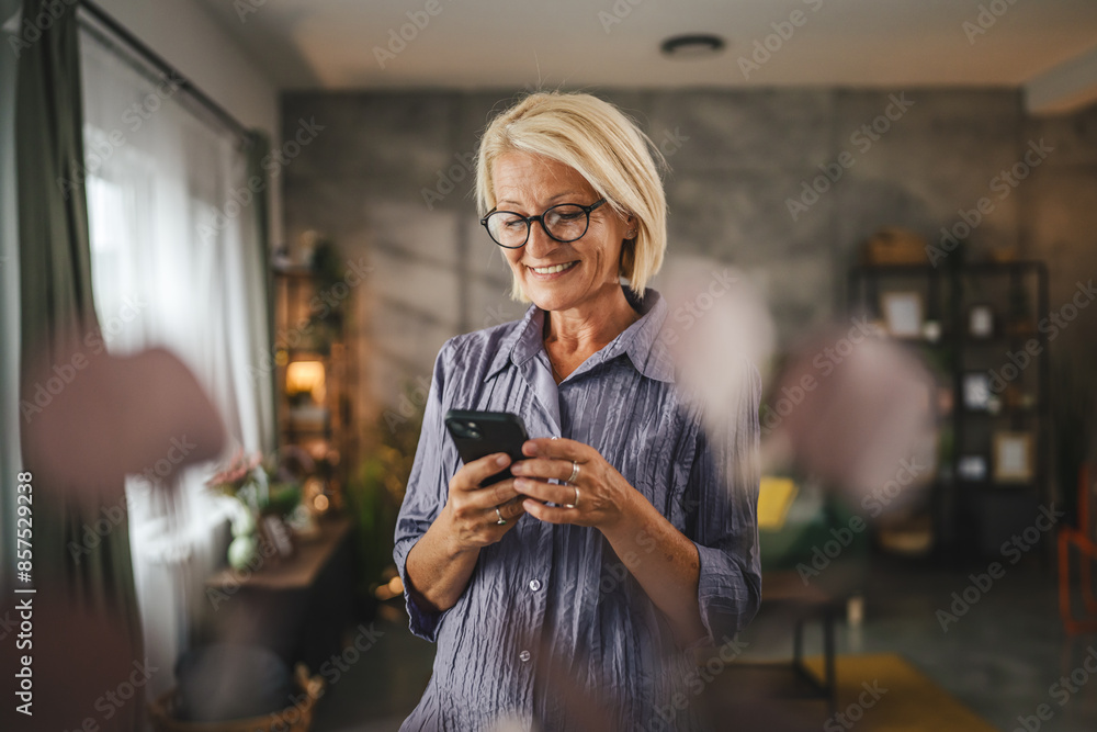 Portrait of mature woman stand and use mobile phone at home Portrait of mature woman stand and use mobile phone at home