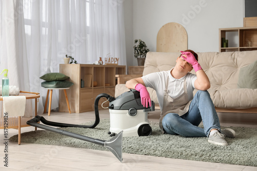 Tired young man with vacuum...