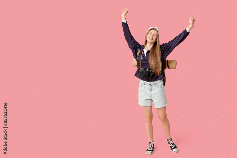 Smiling young woman with camera in case on pink background. Travel concept Smiling young woman with camera in case on pink background. Travel concept