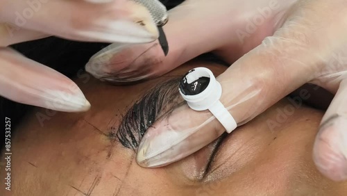 An esthetician using a microblade tool to make small cuts into the eyebrow of a customer. A Microblading technique to implant pigment. Male brow enhancement.