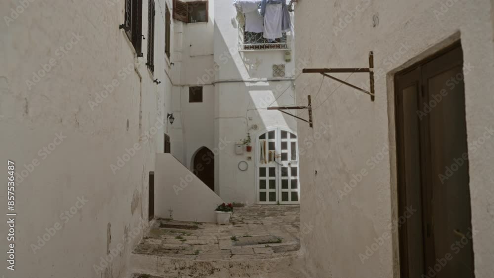 A quaint stone alleyway in ostuni, puglia, italy, featuring white-washed buildings, drying laundry, and charming architecture typical of the mediterranean town. A quaint stone alleyway in ostuni, puglia, italy, featuring white-washed buildings, drying laundry, and charming architecture typical of the mediterranean town.