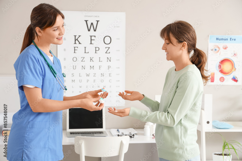 Fototapeta premium Female ophthalmologist giving contact lenses to patient in clinic