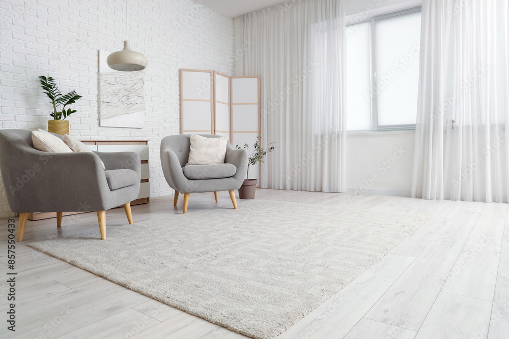 Interior of stylish living room with folding screen, chest of drawers, armchairs and carpet Interior of stylish living room with folding screen, chest of drawers, armchairs and carpet