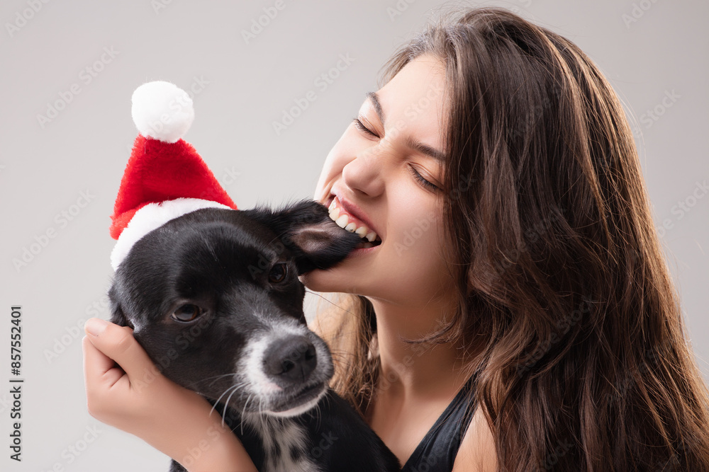 Young woman wearing black is jokingly biting her dog's ear while Young woman wearing black is jokingly biting her dog's ear while
