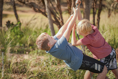 Brothers playing together swinging on rope in the Australian bush photo