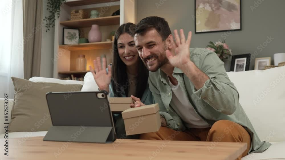 Couple open birthday gift together via video call on tablet at home Couple open birthday gift together via video call on tablet at home