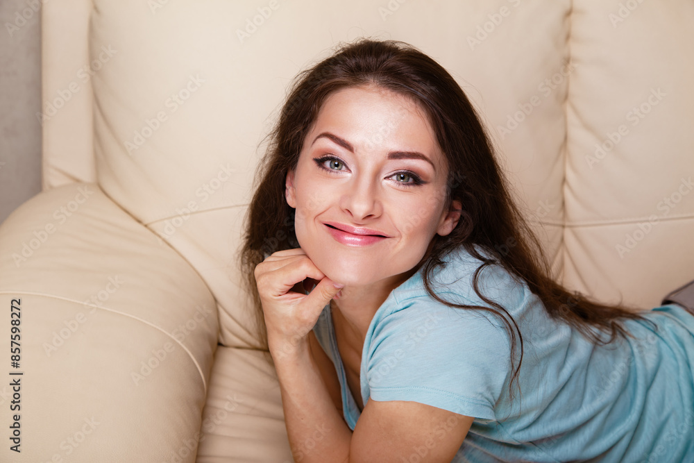 Casual beautiful happy smiling girl relaxing on the sofa and looking in camera Closeup Casual beautiful happy smiling girl relaxing on the sofa and looking in camera Closeup
