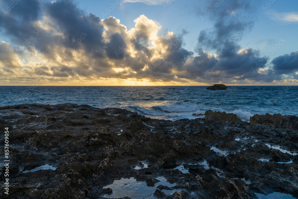 Fototapeta premium Sunrise at the rocky beach in Laie, Hawaii as clouds float in.