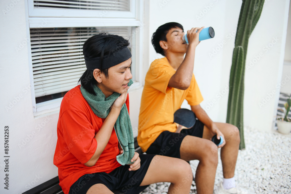 Naklejka premium Tired Two Asian Man Resting After Ping Pong Match With Drinking Water And Wiping Face By Towel