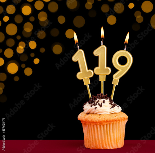 Birthday candle with cupcake - Number 119 on black background with out of focus lights photo