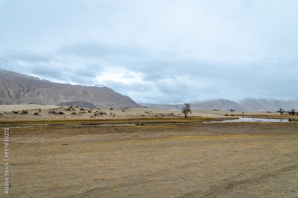 The valley between mountains on a cloudy day. A dried river terrain of Shyok river in Nubra Valley in Ladakh Region of Indian Himalayan territory.A Barren landscape of Cold dessert in Himalaya Valley. The valley between mountains on a cloudy day. A dried river terrain of Shyok river in Nubra Valley in Ladakh Region of Indian Himalayan territory.A Barren landscape of Cold dessert in Himalaya Valley.