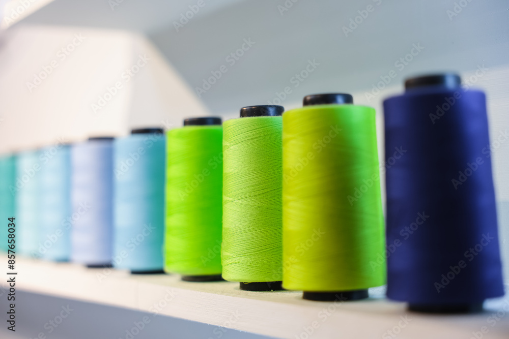 Colorful Spool of sewing thread on the white shelf, isolated on white background. Colored yarns used by factories in the clothing industry. Threads wound on the spool. Colored reels Colorful Spool of sewing thread on the white shelf, isolated on white background. Colored yarns used by factories in the clothing industry. Threads wound on the spool. Colored reels