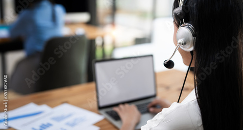 Rear view of Young  operator woman agent with headsets working in a call centre. photo