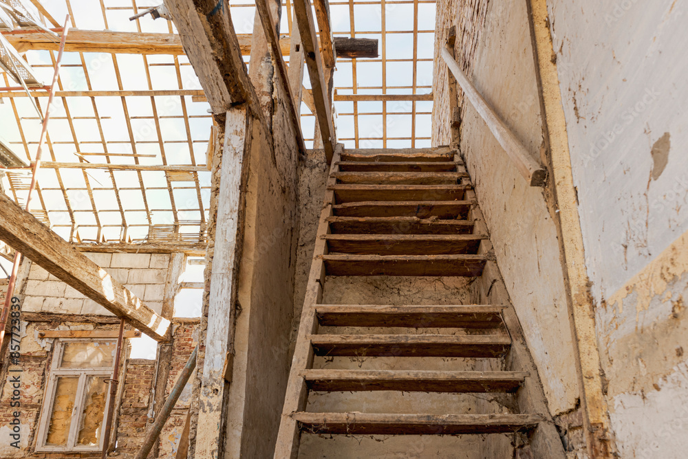 The interior of an old house undergoing major renovation and complete roof replacement. A broken wooden frame and ladder to the floor. The interior of an old house undergoing major renovation and complete roof replacement. A broken wooden frame and ladder to the floor.