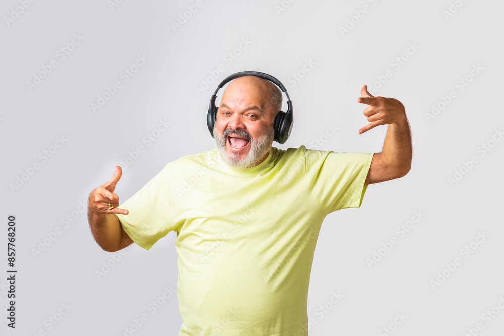 Naklejka premium Senior elderly retired Indian asian man wears headphone and listening to music and dancing on beats against white background