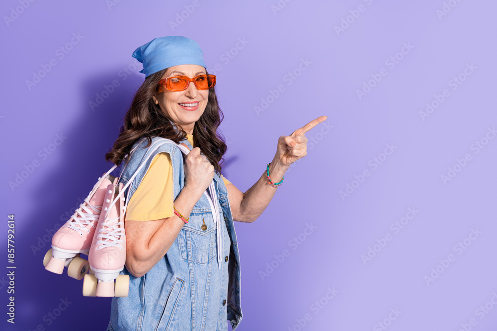 Photo of lovely pensioner lady roller skater point empty space dressed stylish denim hipster garment isolated on purple color background Photo of lovely pensioner lady roller skater point empty space dressed stylish denim hipster garment isolated on purple color background